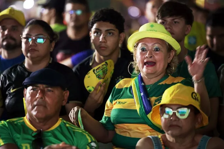 Brazil football fans in a crowd react with tense expressions as they watch a match on a screen in Manaus, Brazil